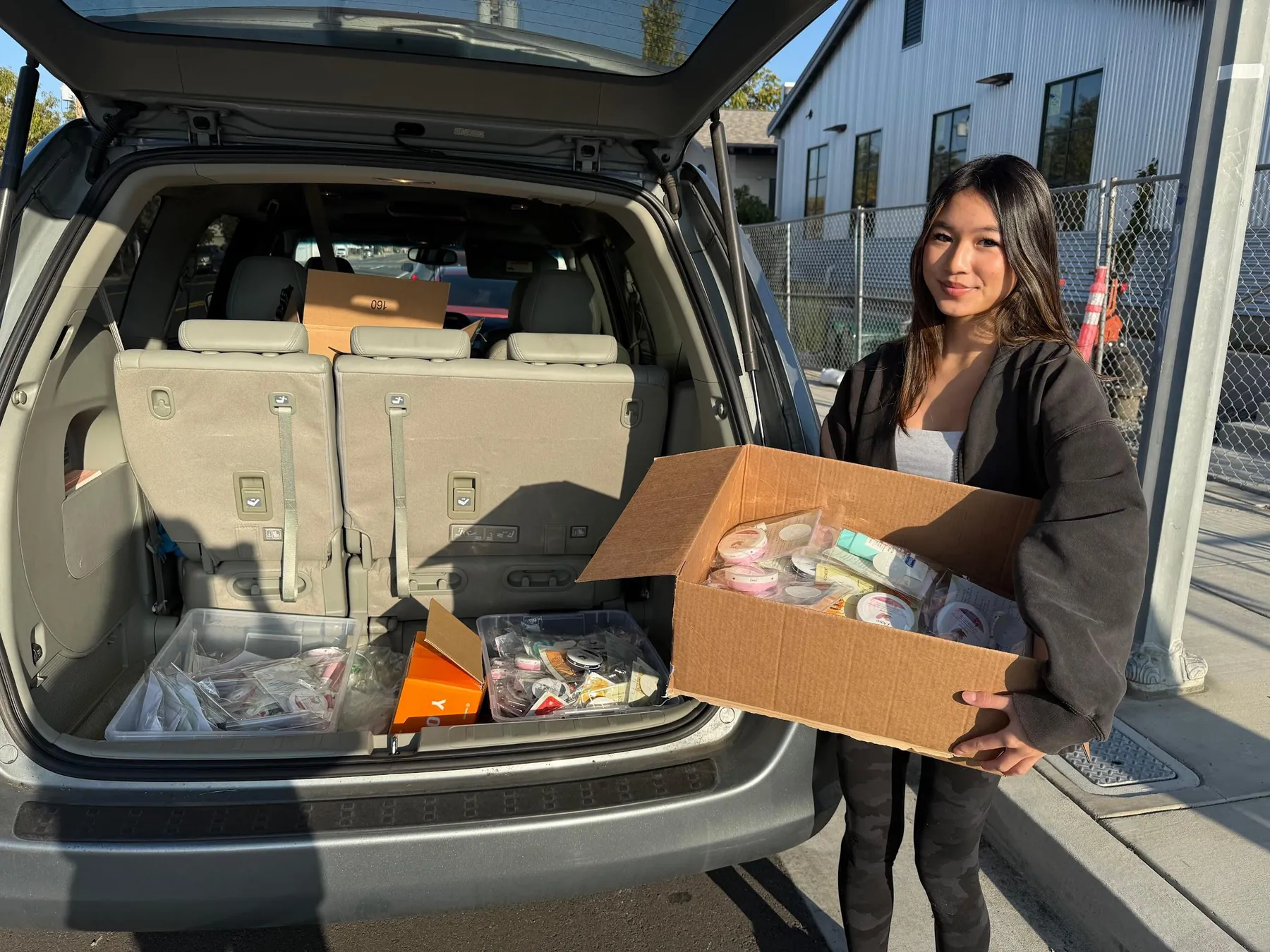 Founder loading boxes of skincare kits for a community distribution.